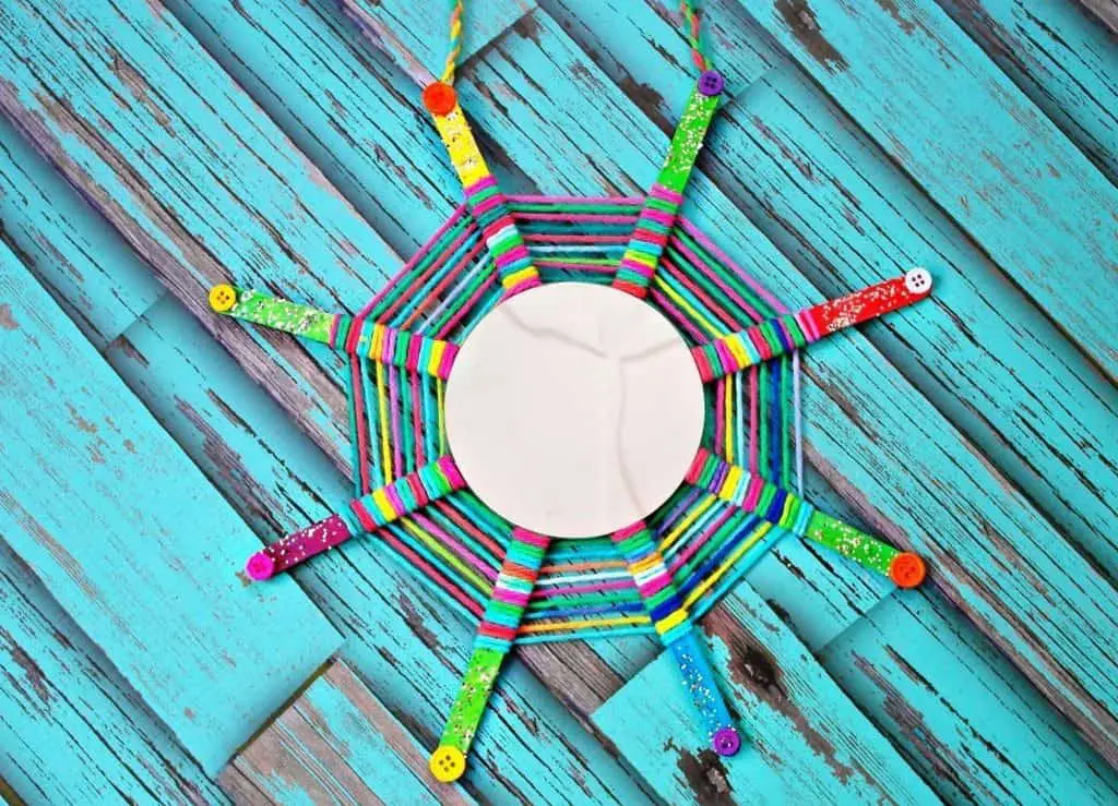 this God's Eye craft is an update on the classic craft featuring popsicle sticks and string. We added a mirror and hung them in multiples for fun decor!