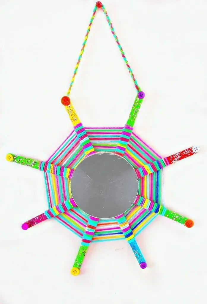 this God's Eye craft is an update on the classic craft featuring popsicle sticks and string. We added a mirror and hung them in multiples for fun decor!