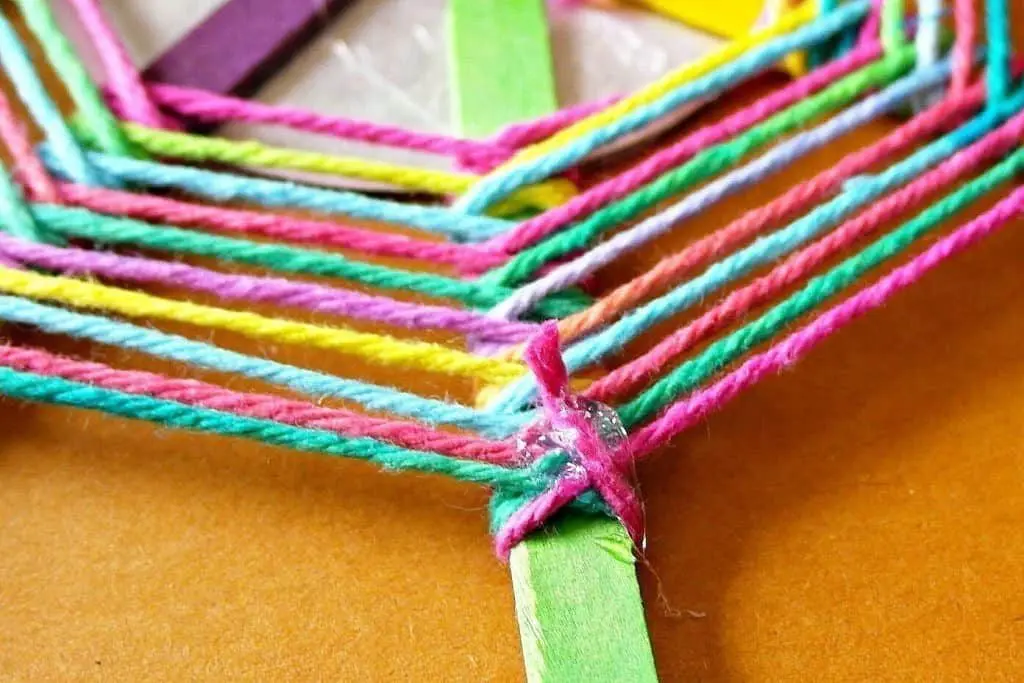 this God's Eye craft is an update on the classic craft featuring popsicle sticks and string. We added a mirror and hung them in multiples for fun decor!