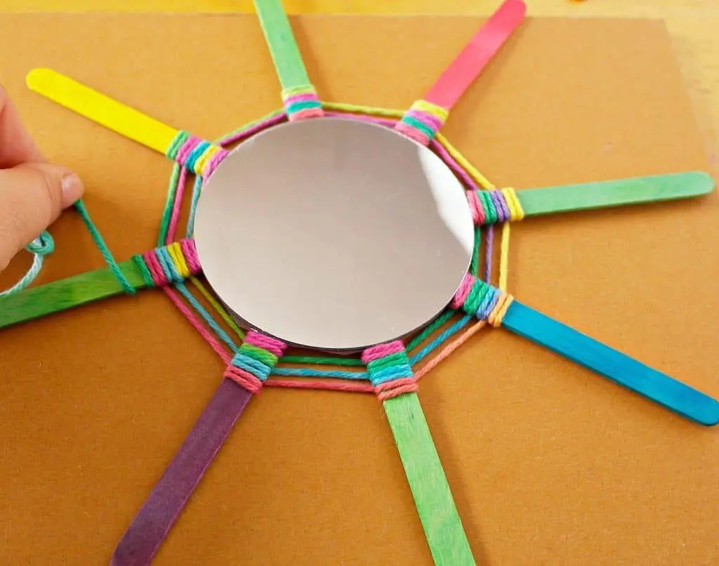 this God's Eye craft is an update on the classic craft featuring popsicle sticks and string. We added a mirror and hung them in multiples for fun decor!