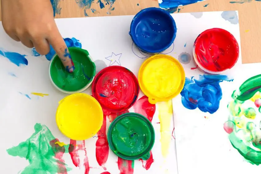 48541554 - colorful finger paints with childrent hand on a table