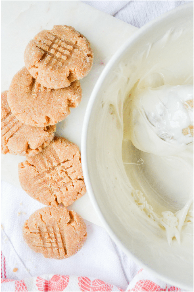 a bowl of homemade marshmallow cream with homemade peanut butter cookies along side.