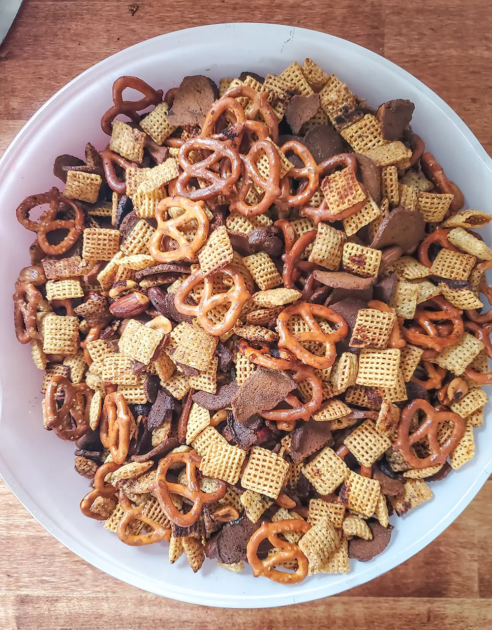 Homemade chex mix with Chex cereal, rye crackers, pretzels, mixed nuts, butter, and seasonings.