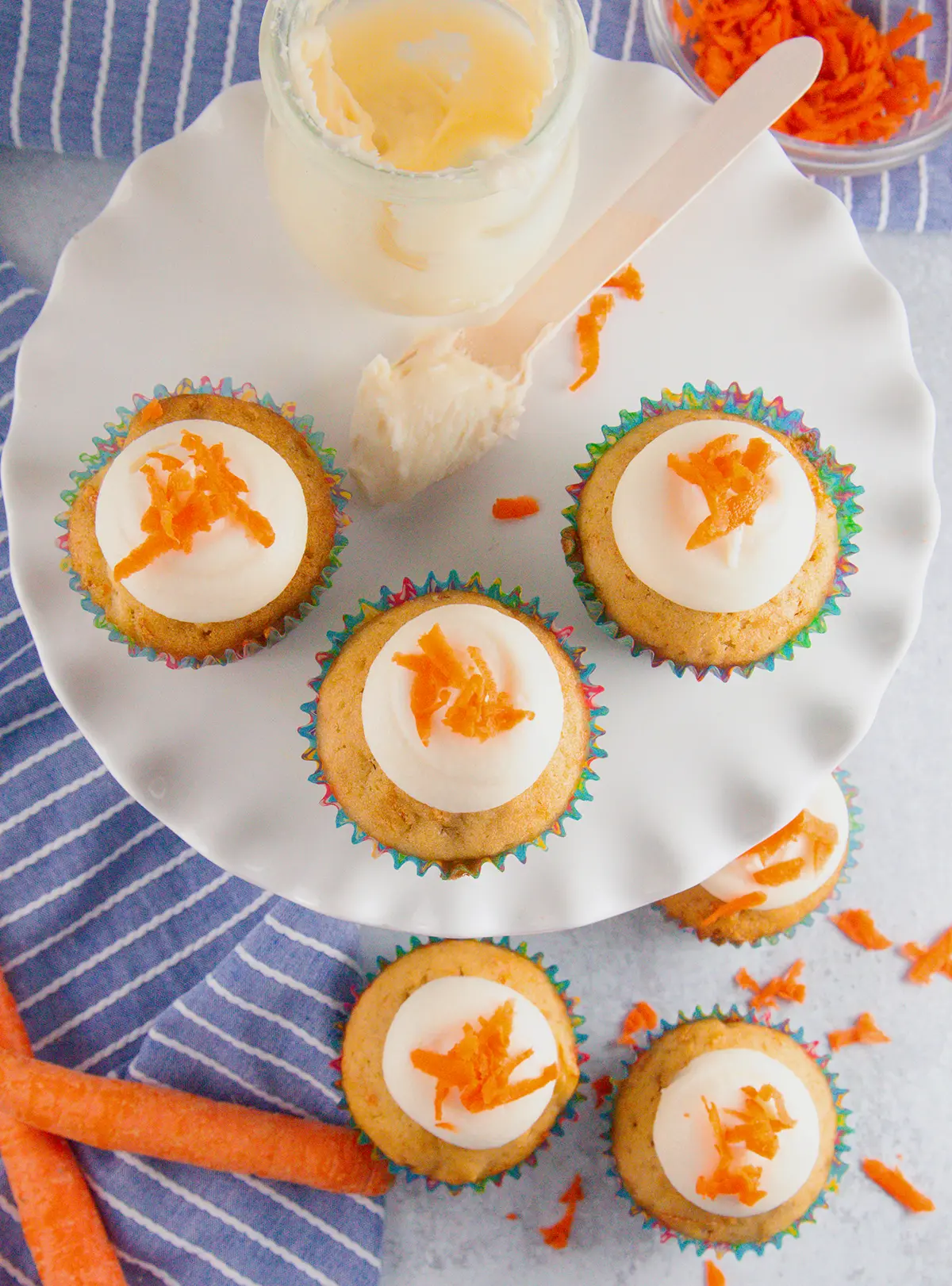A yummy plate full of cream cheese frosting topped carrot cupcakes