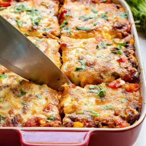 cutting into a mexican tortilla casserole