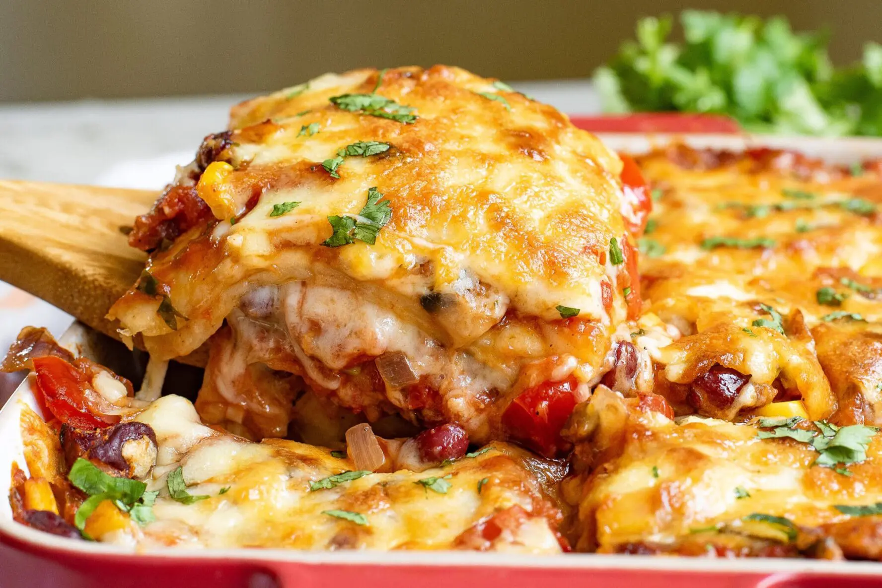 a slice of mexican tortilla casserole being taken out of the pan