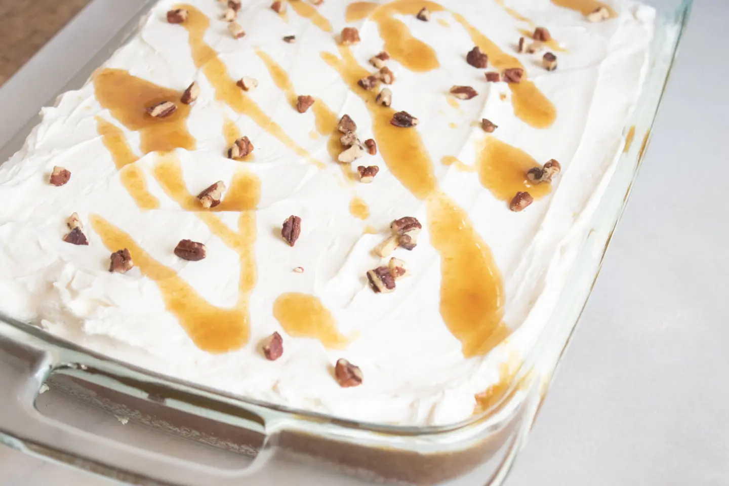 Pumpkin Poke Cake with whipped cream cheese frosting and drizzled with homemade caramel