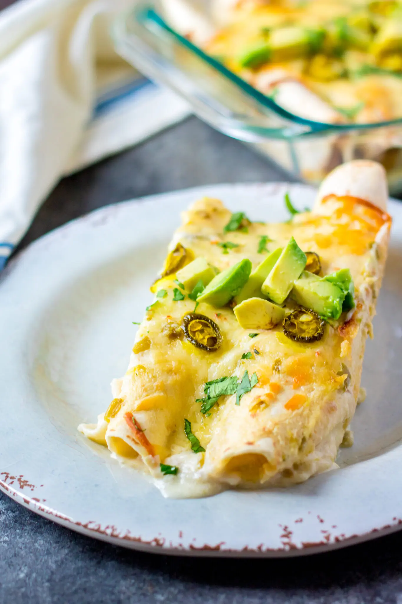 A serving of 2 chicken enchiladas with white sauce.