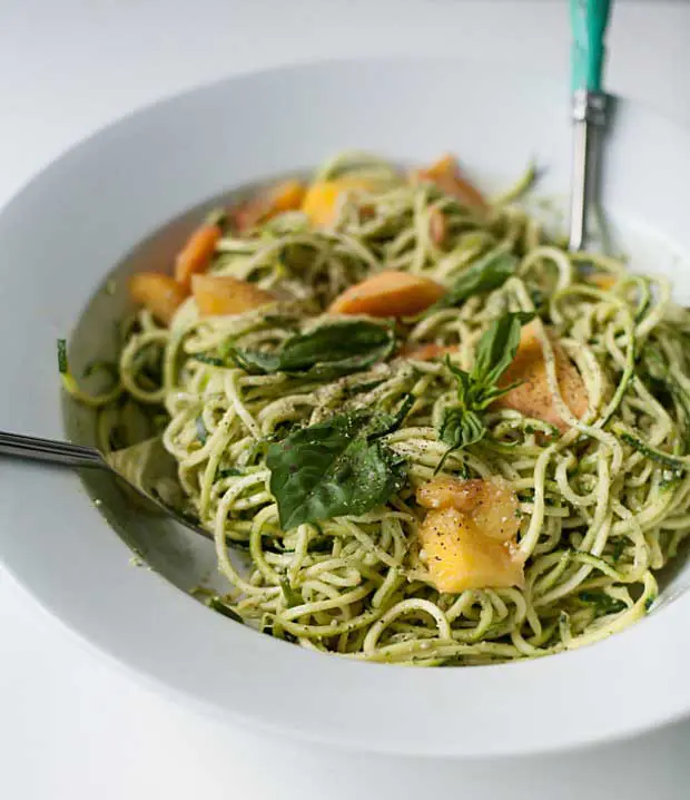 Bowl of zucchini noodles with pumpkin seed pesto and peaches