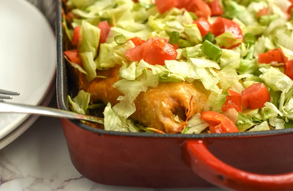 dorito casserole in a pan topped with taco fixings