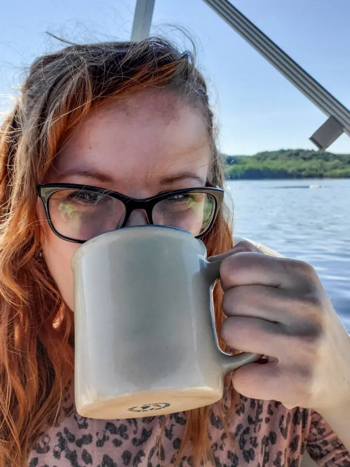 Janel drinking coffee out on the river