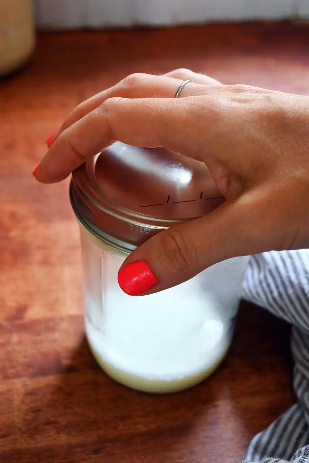 Putting the lid on a mason jar with a bit of milk in it.