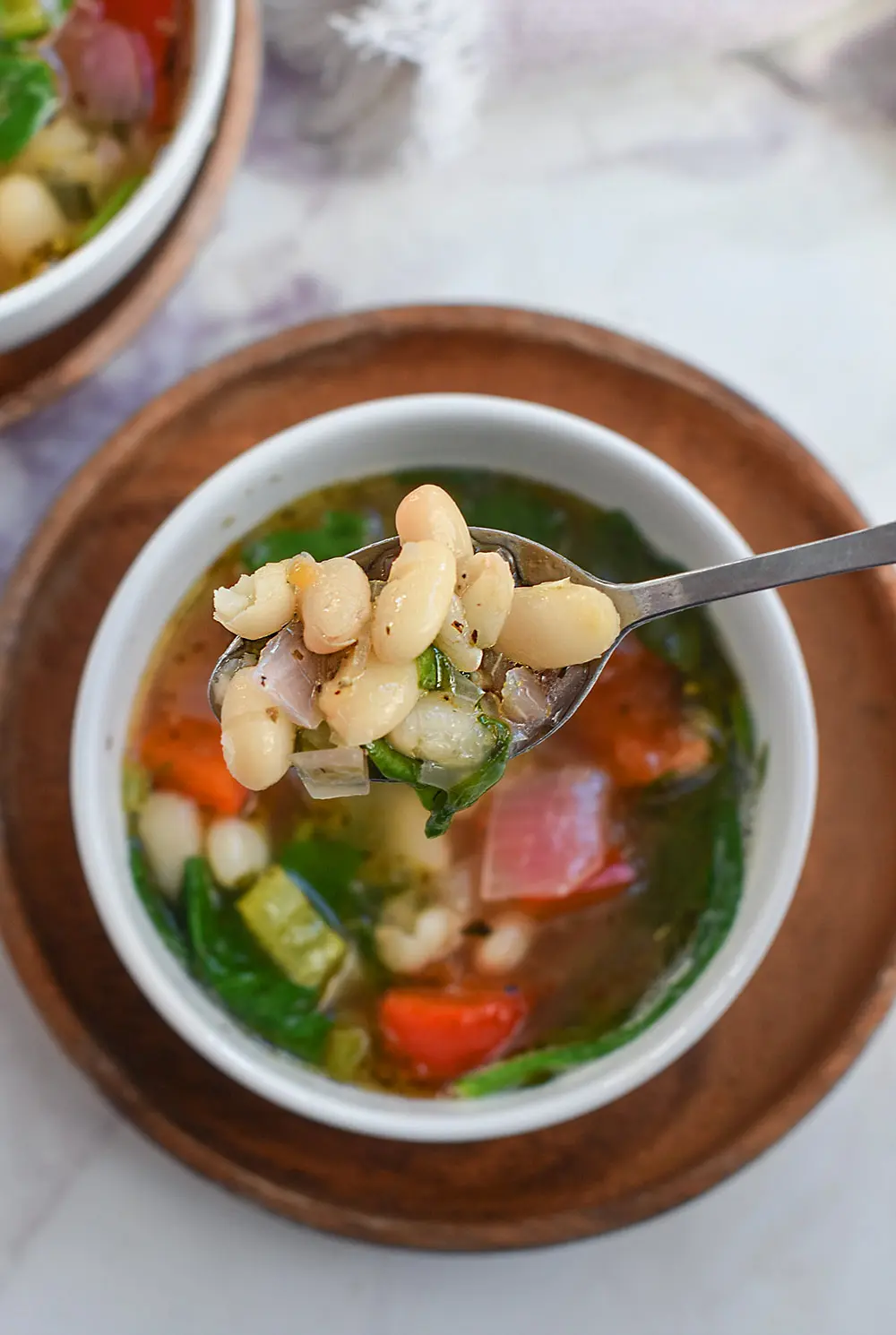 a spoonful of white bean soup full of veggies.