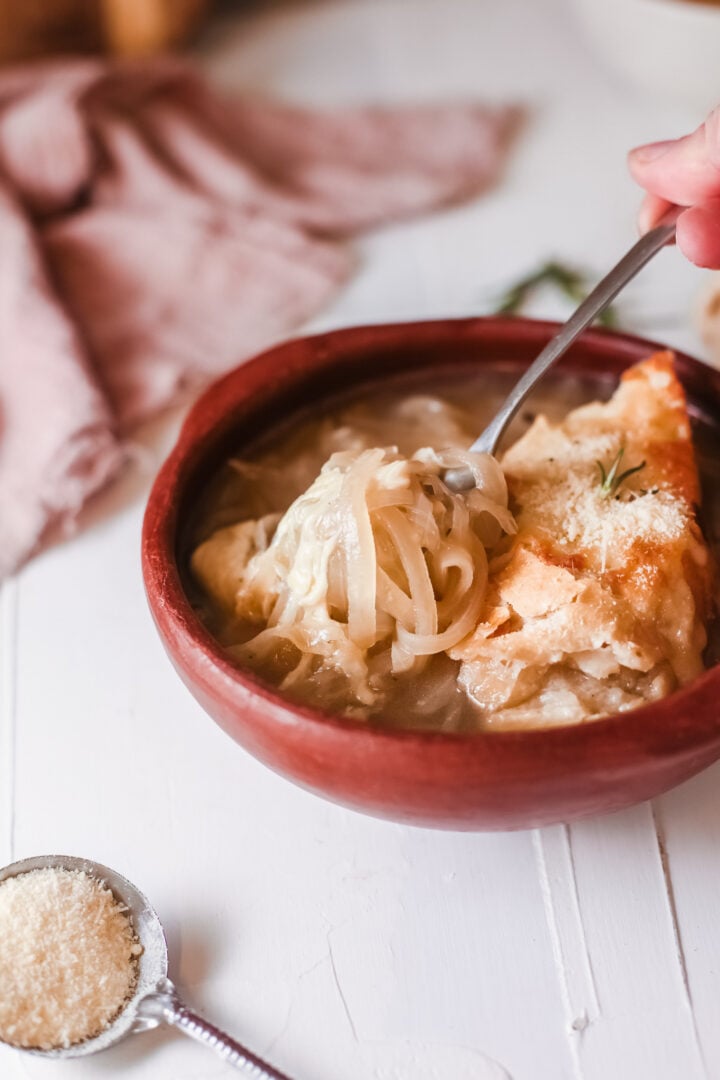 A forkful of onion soup with crusty bread and cheesel