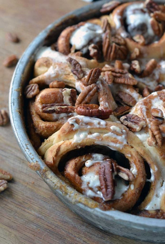 a pan of cinnamon rolls with nuts and frosting