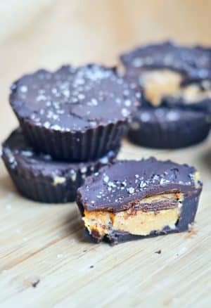 homemade peanut butter cups stacked and one is cut open showing the yummy peanut butter center