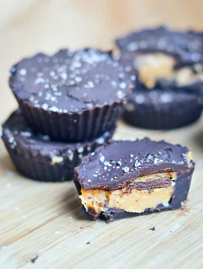 homemade peanut butter cups stacked and one is cut open showing the yummy peanut butter center