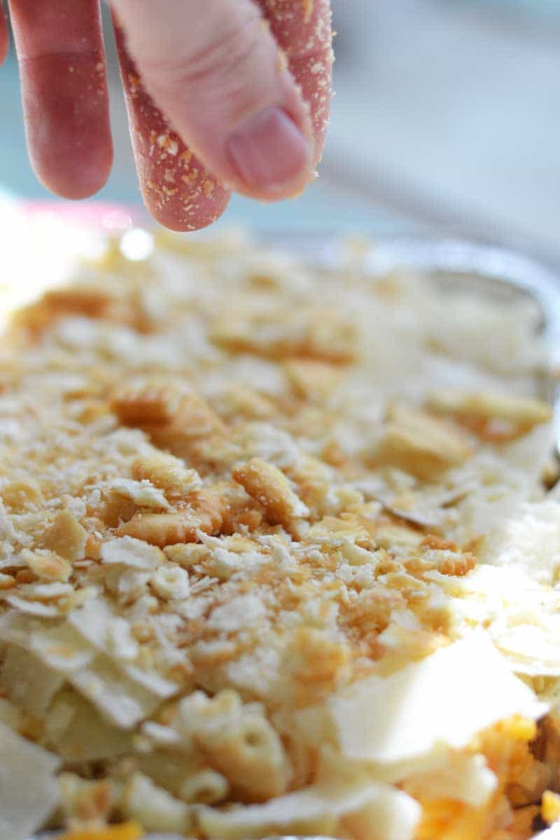 sprinkling crackers on macaroni and cheese for the campfire