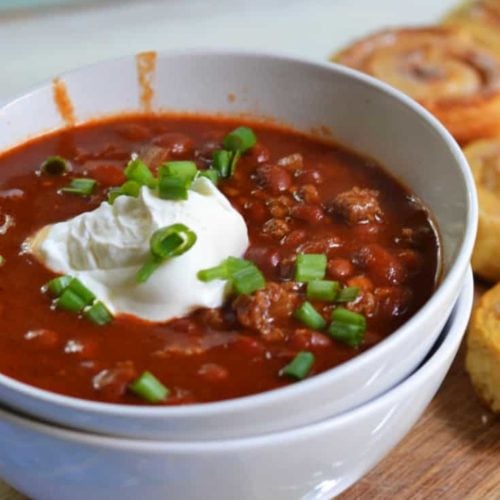 venison chili in a bowl topped with sour cream and green onions