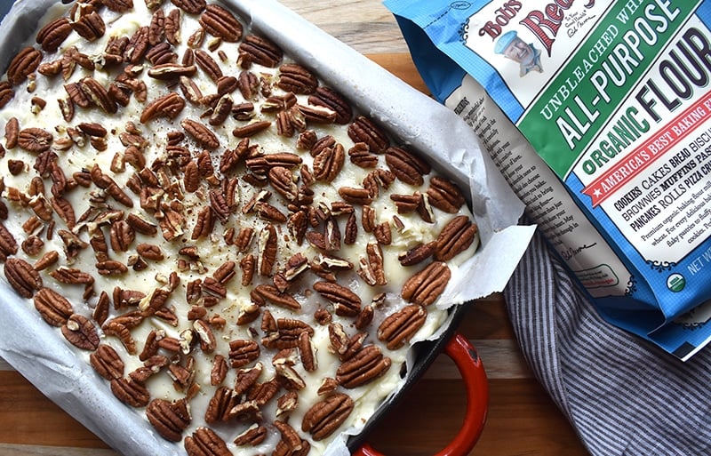 a pan of pineapple cake topped with cream cheese frosting and pecans.