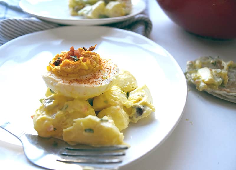 potato salad with a deviled egg on top looking good enough to eat on a plate!