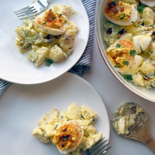 deviled egg potato salad on two plates with forks
