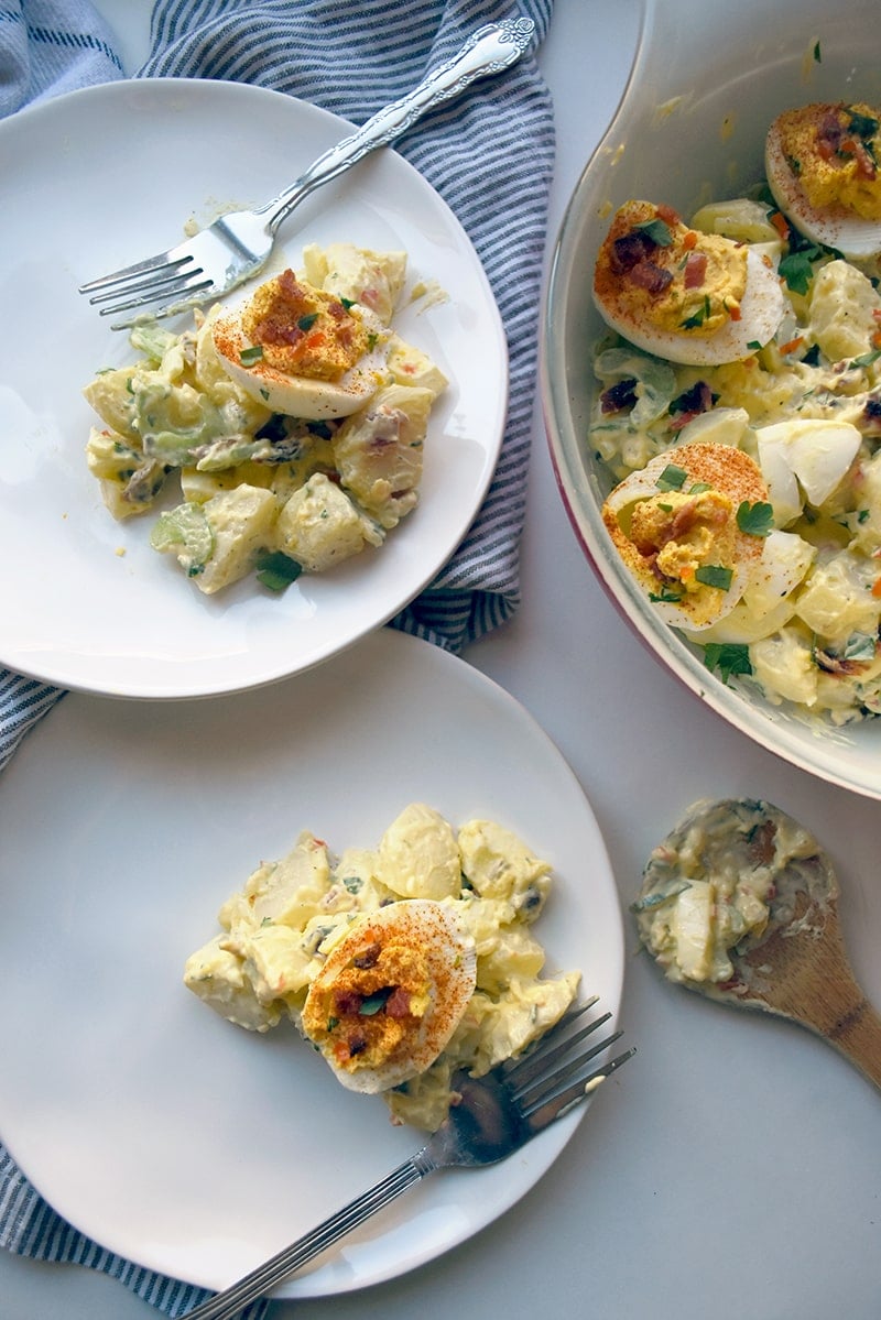 deviled egg potato salad on two plates with forks