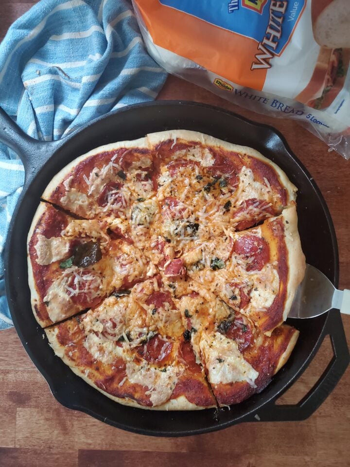 serving up a slice of cast iron deep dish pizza from a cast iron pan