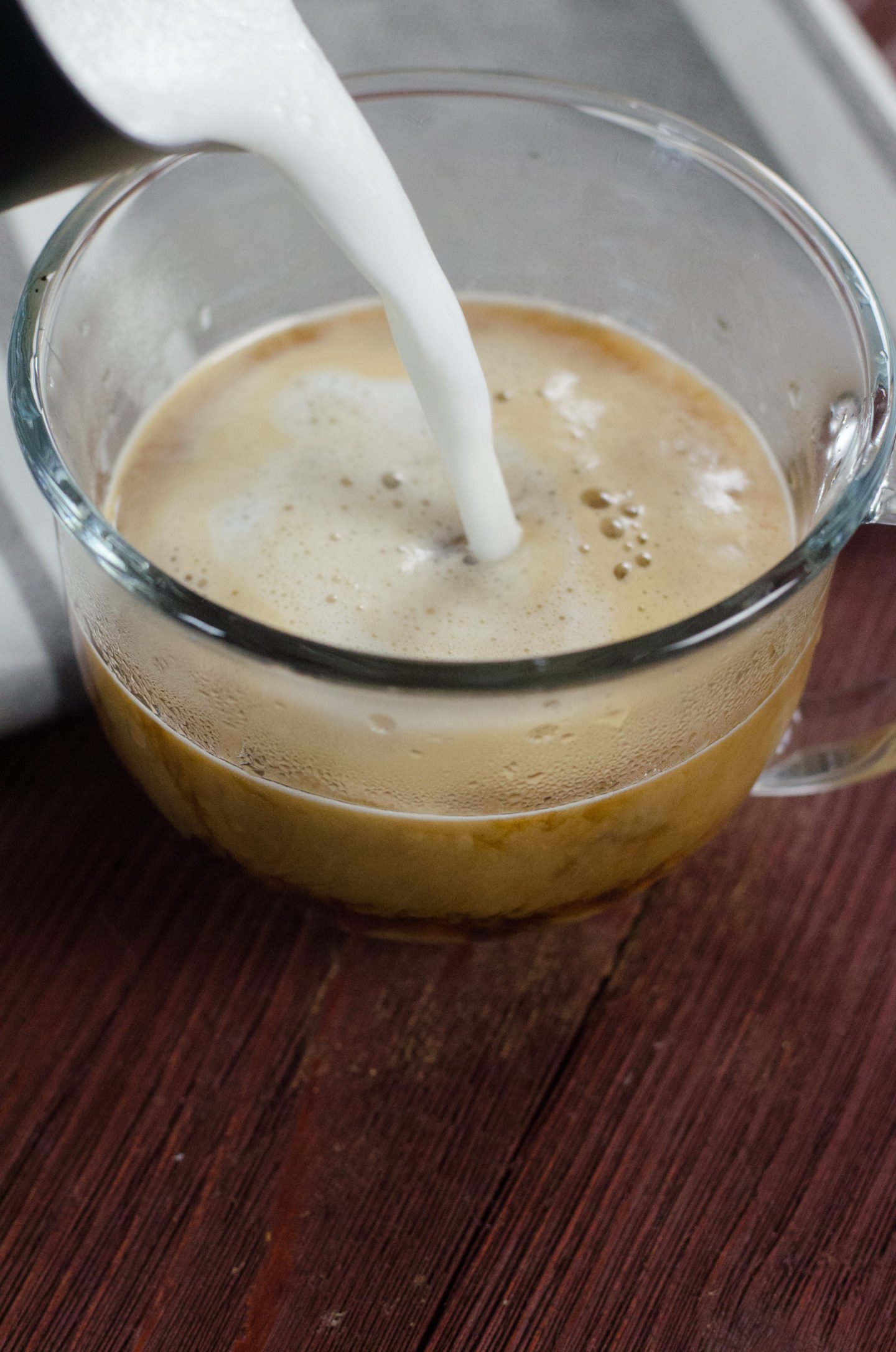 Maple cappuccino with milk being poured in.