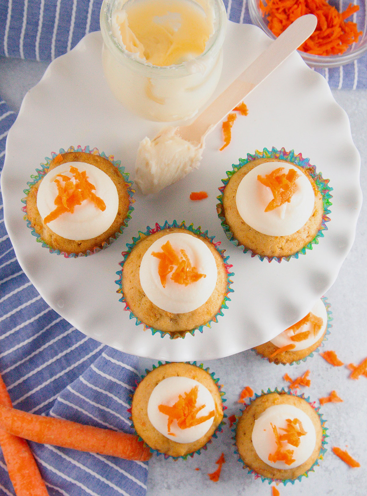 A yummy plate full of cream cheese frosting topped carrot cupcakes