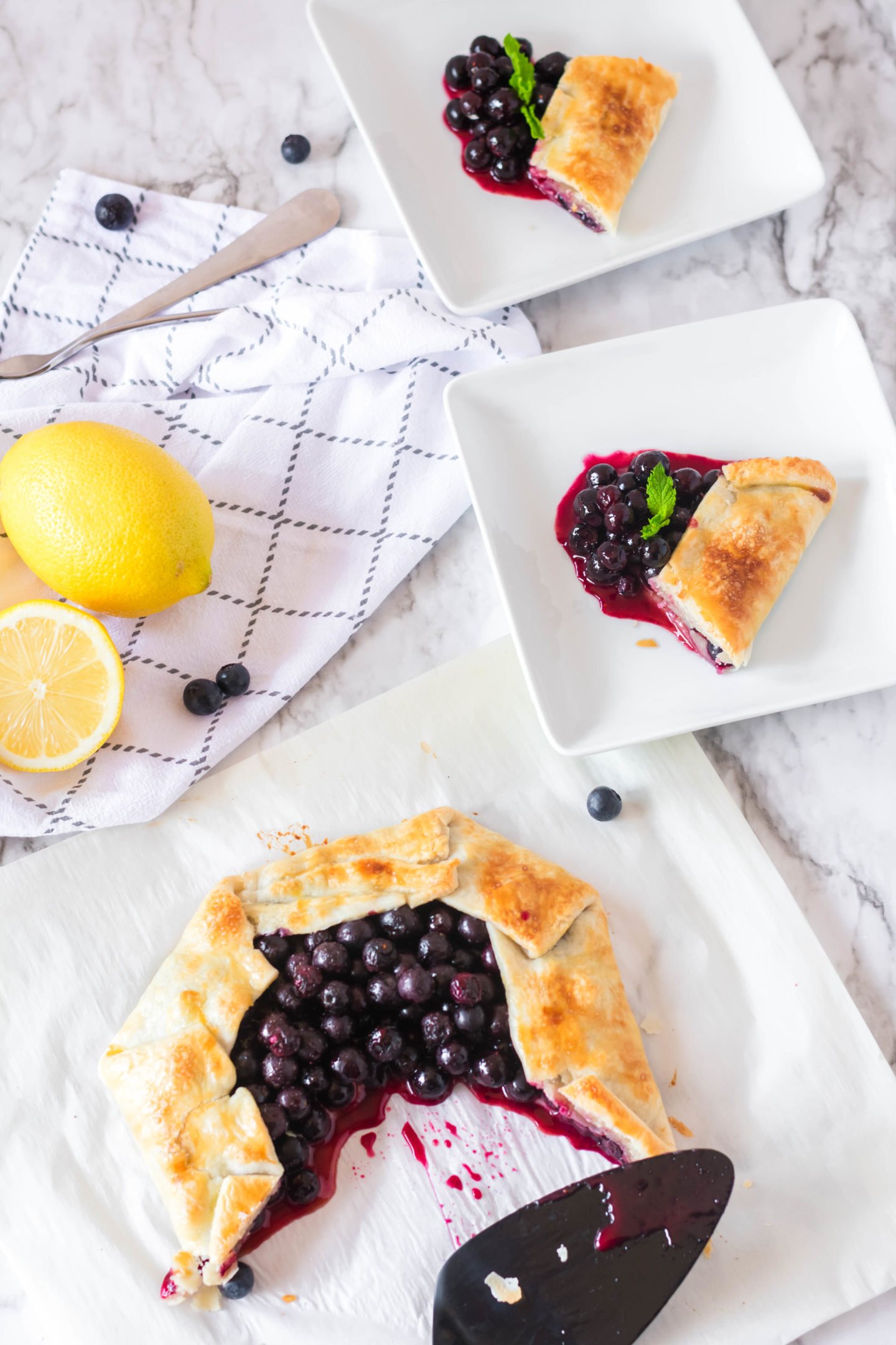 Rustic fresh blueberry tart served up on dishes for sharing. 