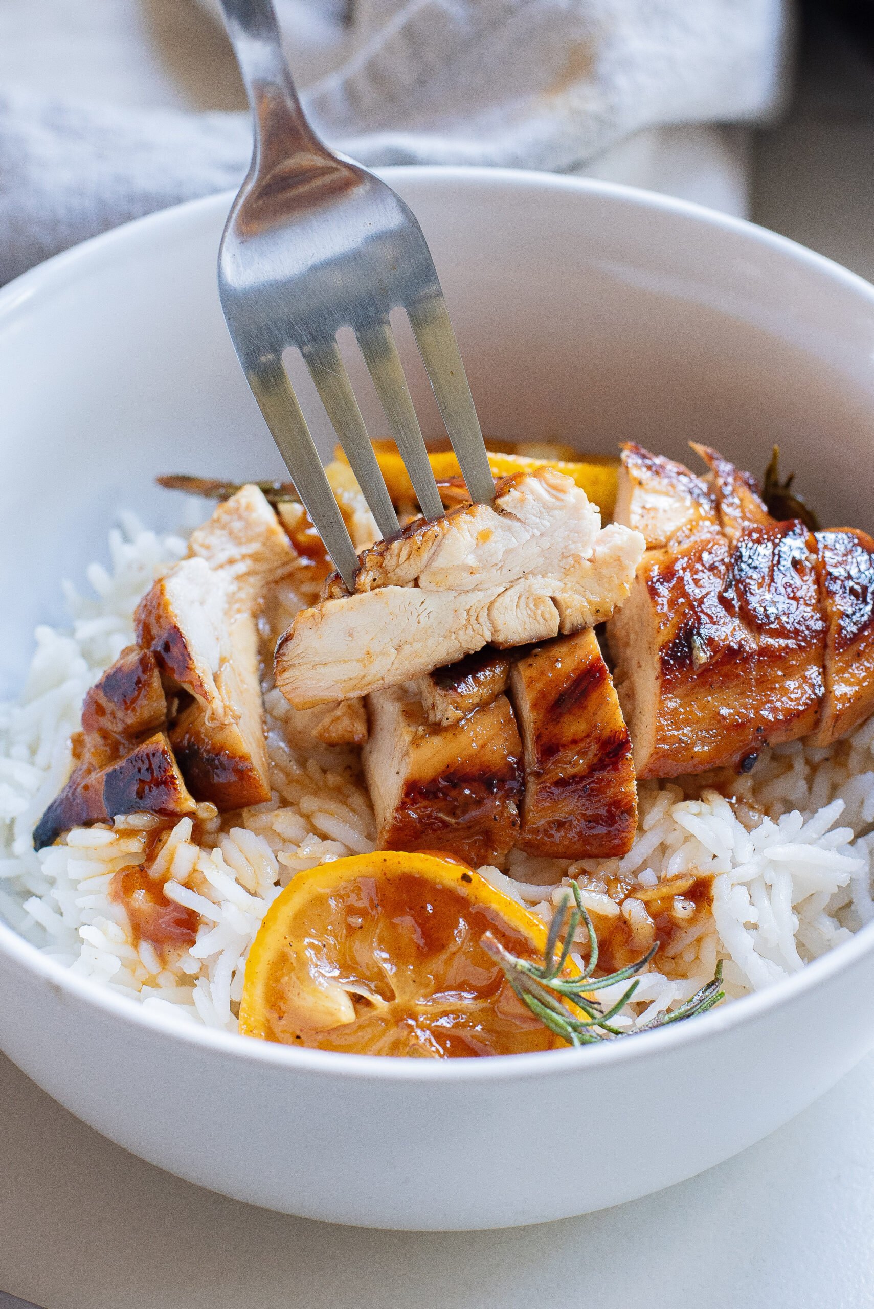 a forkful of honey lemon rosemary chicken served over rice