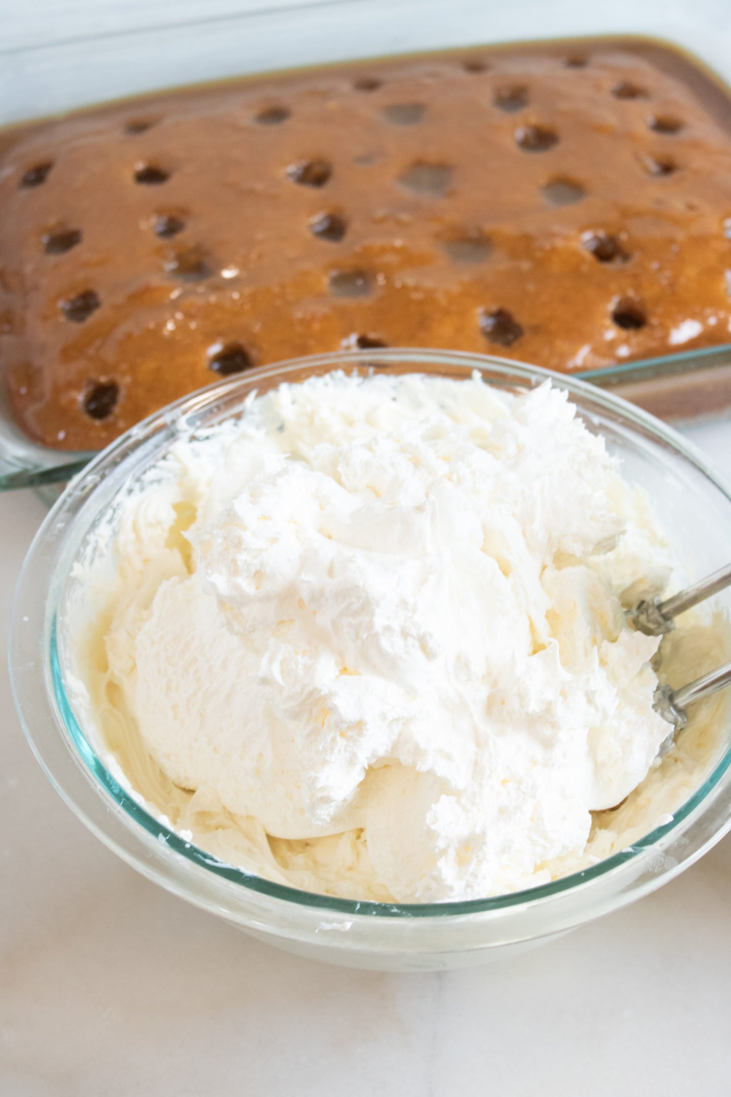 Pumpkin Poke cake with the holes filled with homemade caramel and ready for the fluffy cream cheese frosting