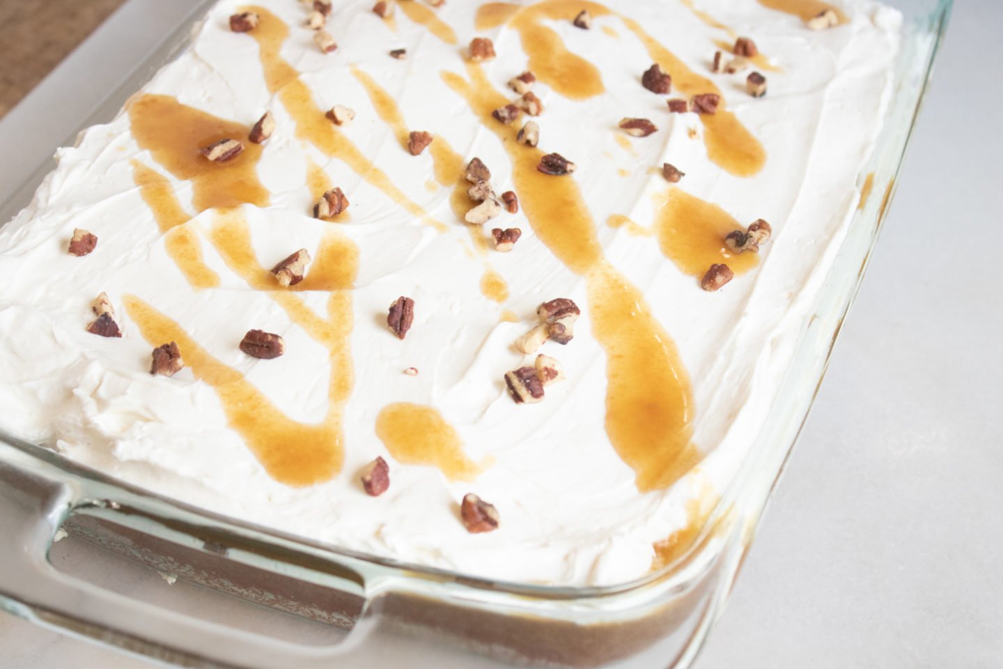 Pumpkin Poke Cake with whipped cream cheese frosting and drizzled with homemade caramel