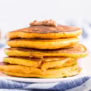 A stack of pumpkin pancakes with a dollup of cinnamon butter on the top.