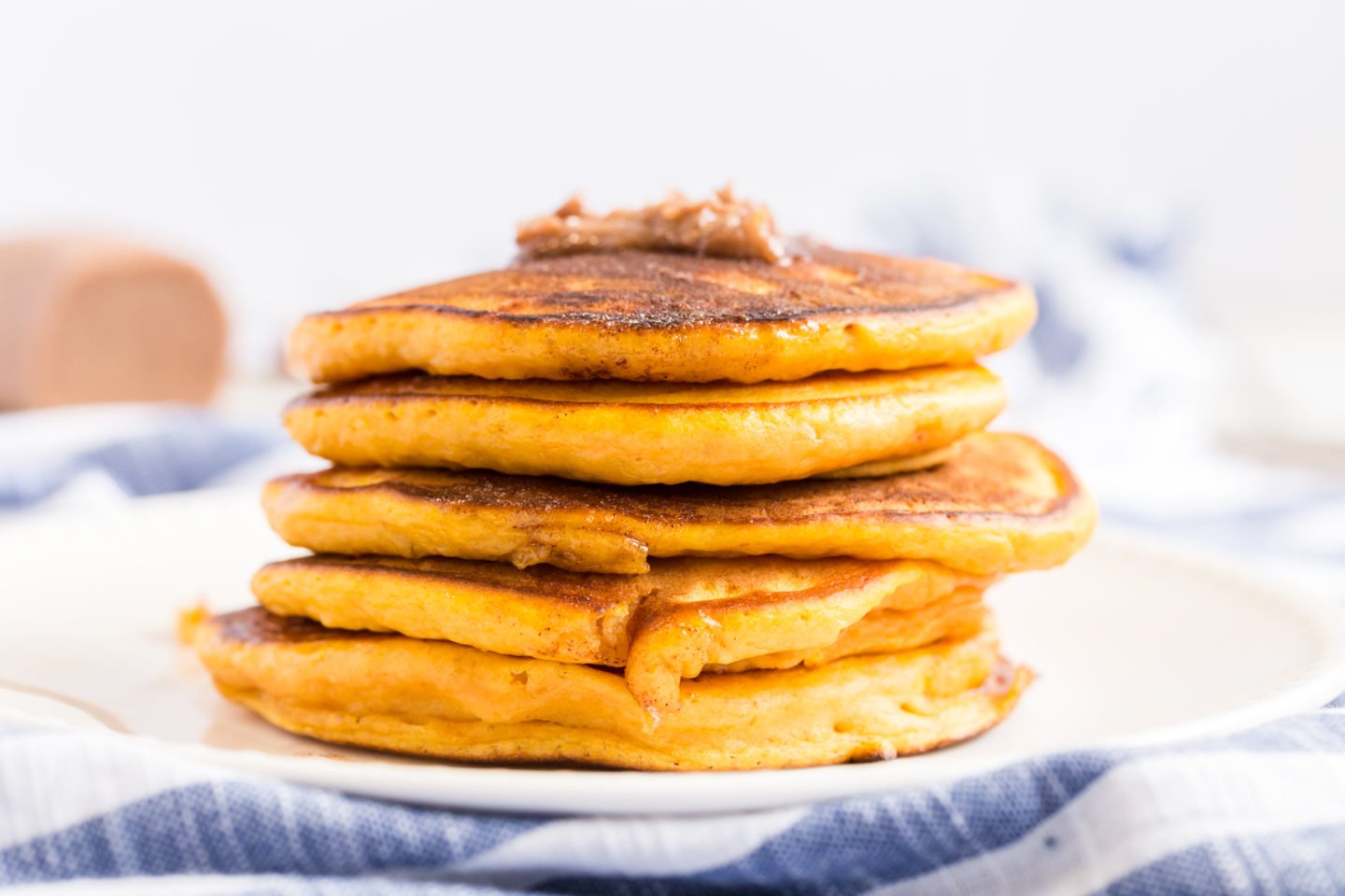 A stack of pumpkin pancakes with a dollup of cinnamon butter on the top.