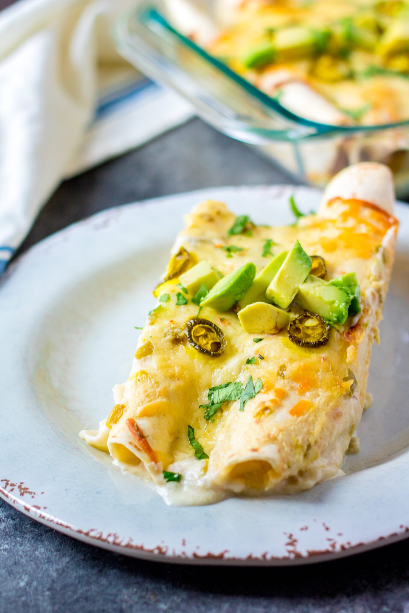 A serving of 2 chicken enchiladas with white sauce.