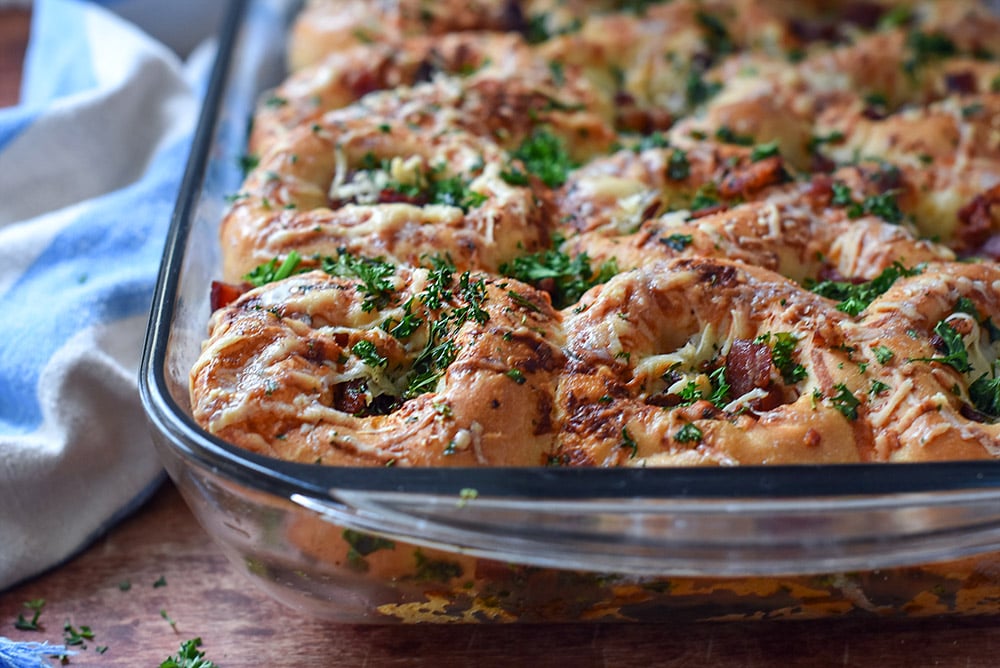 Rhodes frozen dinner rolls topped with crispy bacon, cheese, and fresh parsley.