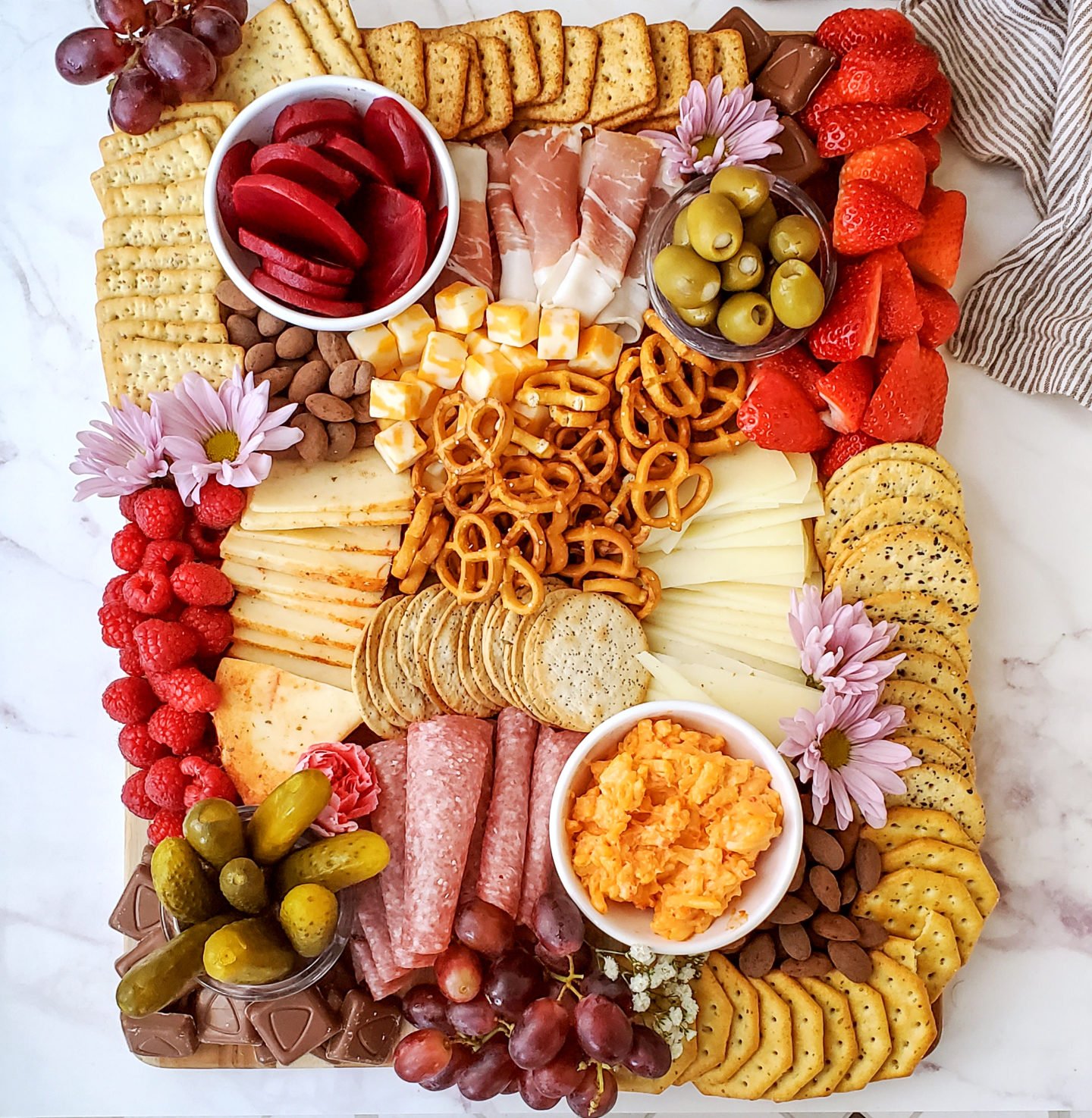 Charcuterie board full of meats, cheeses, veggies, crackers, and more