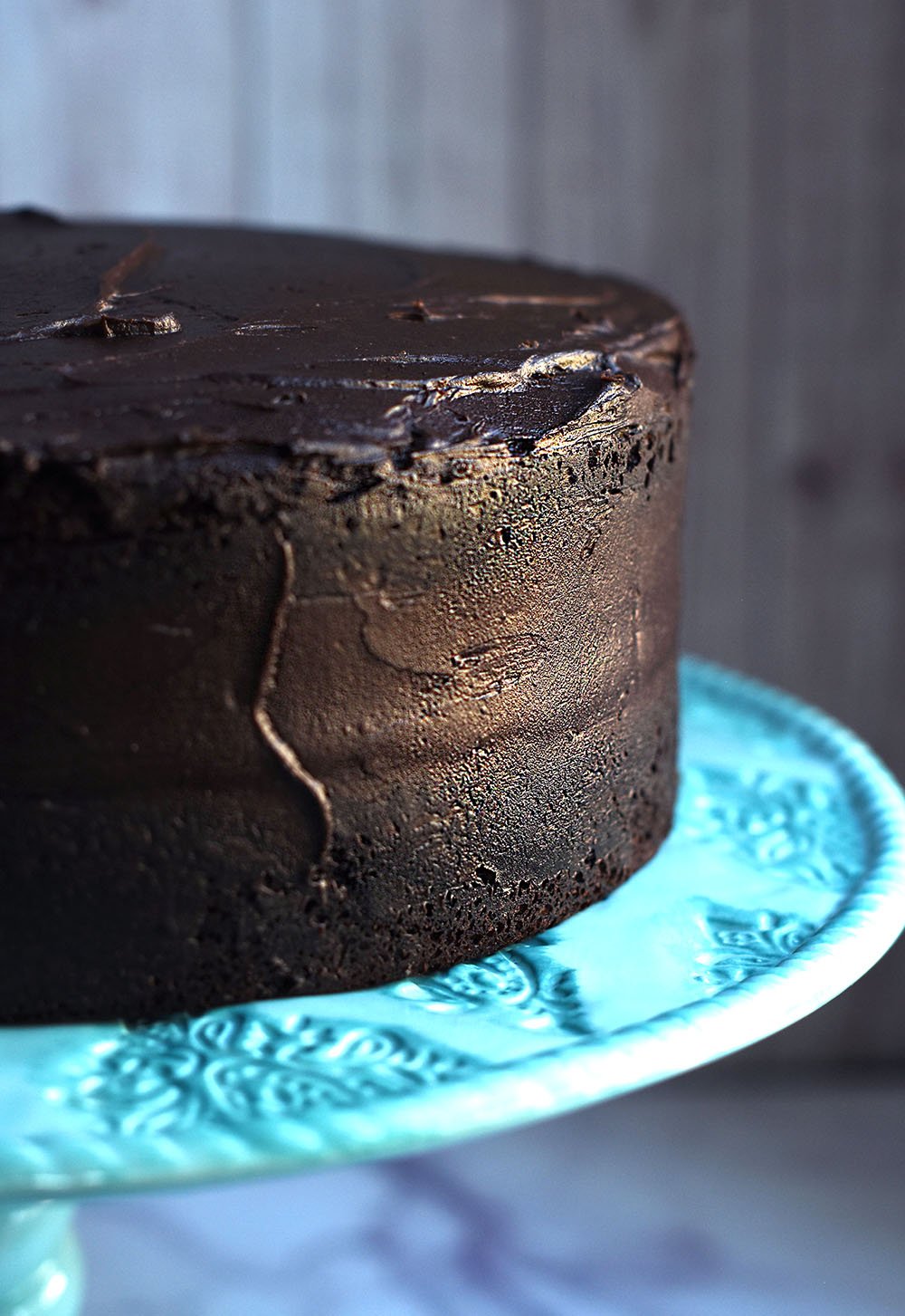 homemade chocolate cake with frosting on a cake platter