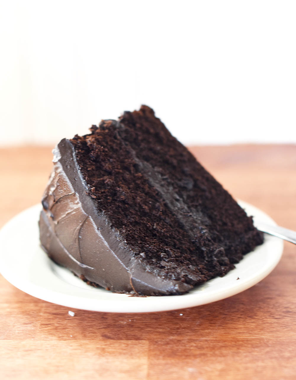 A slice of homemade chocolate cake with chocolate frosting on a plate