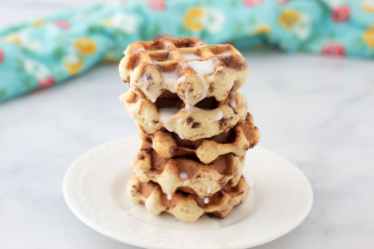 A plate of cinnamon roll waffles with cream cheese frosting on them.