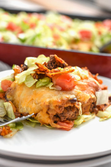 Dorito pie or casserole on a plate with a pan in the background. An easy family friendly meal!