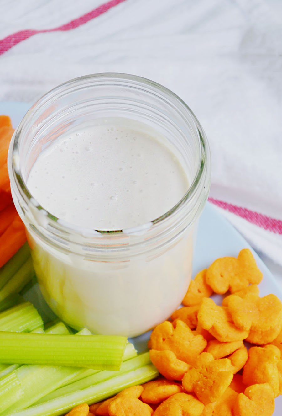 Creamy homemade blue cheese dressing in a jar with celery and carrots.