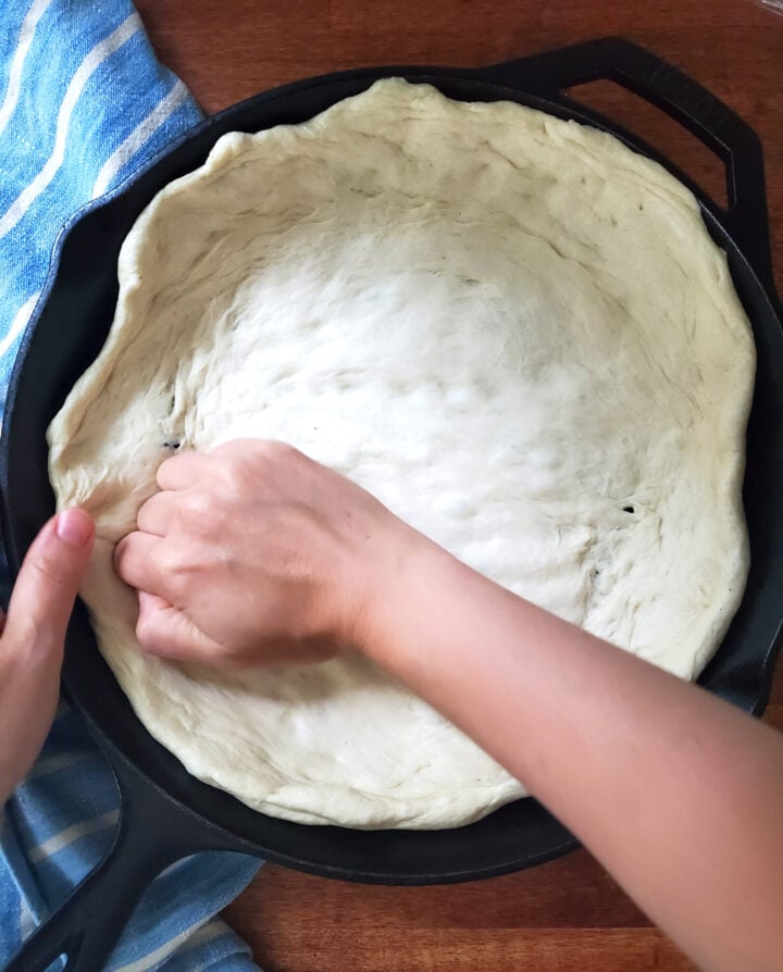 pressing Rhodes frozen bread dough into a cast iron pan