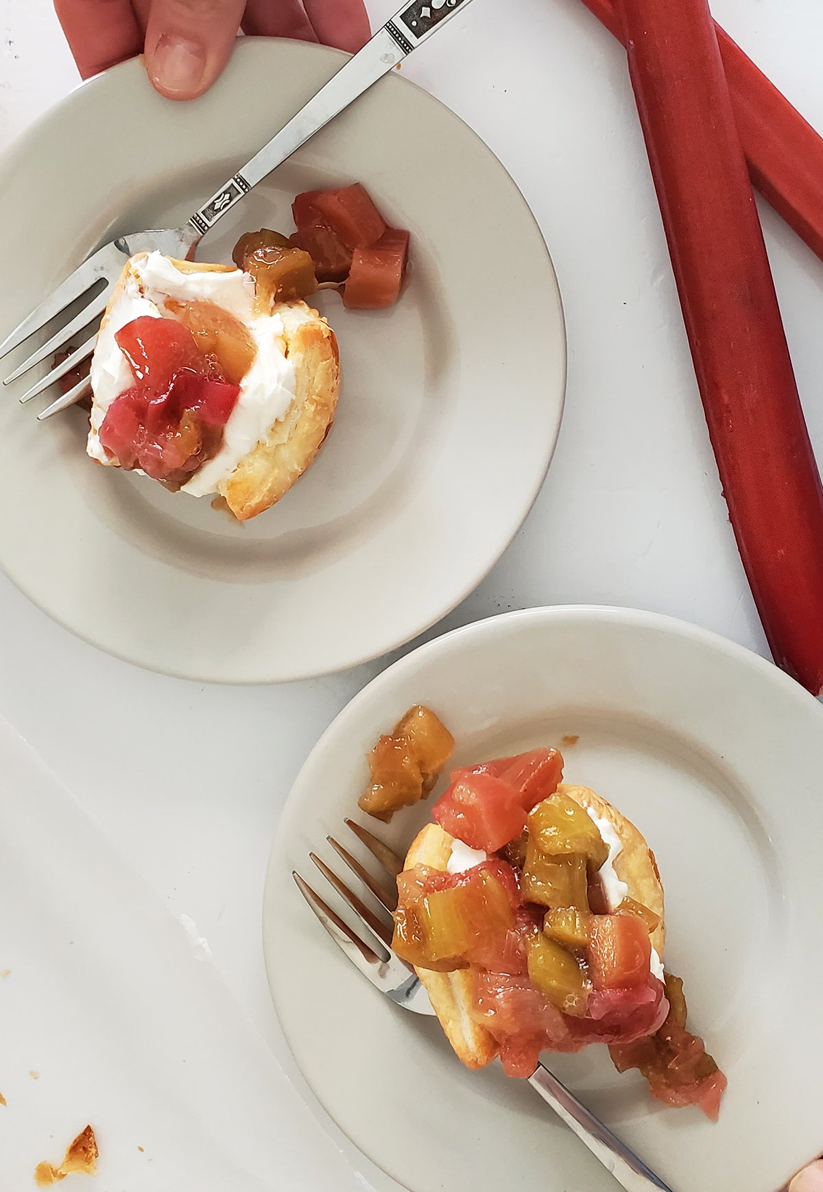two rhubarb tartlets on plates with forks