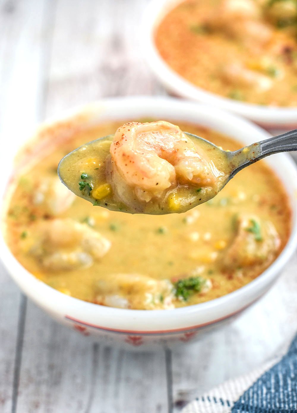 A bowl of shrimp and corn chowder with a bit on a spoon